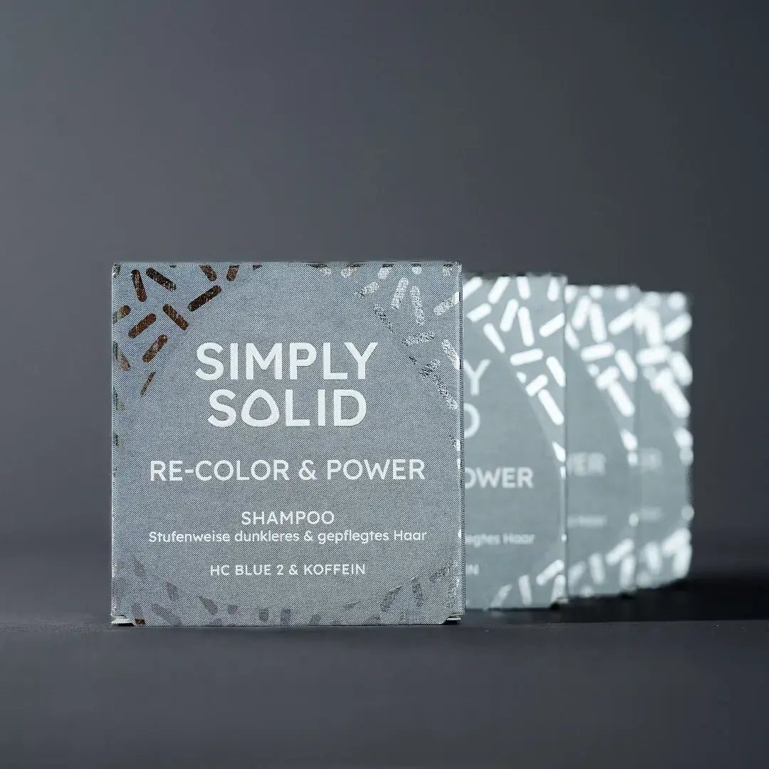 Re-Color and Power Verpackungen aufgereiht vor einem grauen Hintergrund