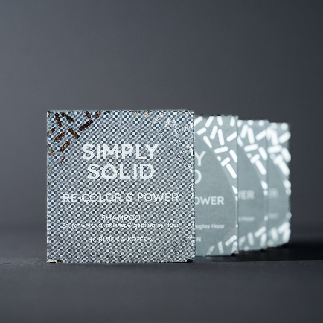 Re-Color and Power Verpackungen aufgereiht vor einem grauen Hintergrund