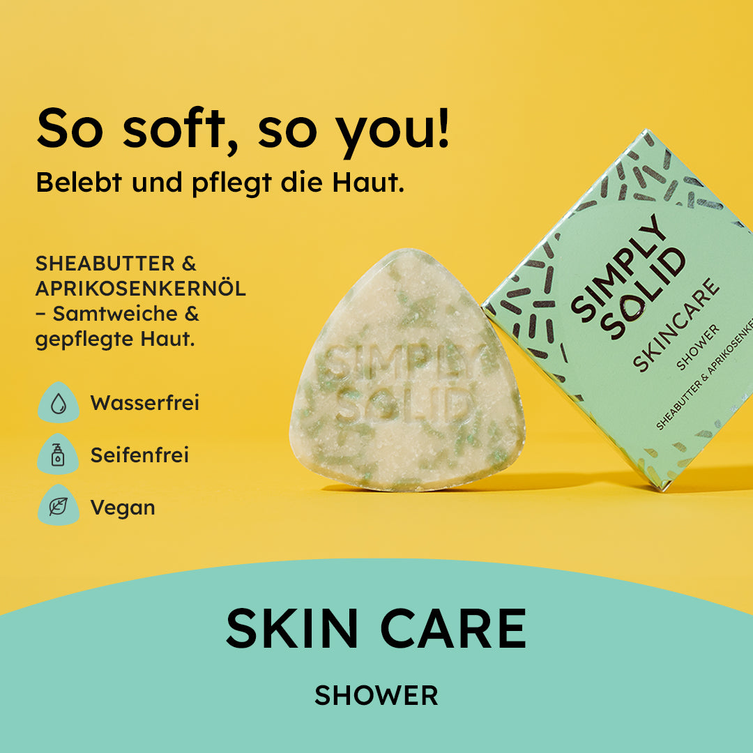 Simply Solid Skin Care Dusch-Solid in Dreiecksform neben der Verpackung auf gelbem Hintergrund. Der Claim „So soft, so you!“ betont die sanfte Pflegewirkung. Mit Sheabutter und Aprikosenkernöl sorgt das Solid für samtweiche Haut. Das Produkt ist wasserfrei, seifenfrei, vegan und plastikfrei, und verkörpert die nachhaltige Philosophie von Simply Solid. Die türkisfarbene Verpackung hebt sich vom gelben Hintergrund ab und verstärkt die frische Ästhetik.