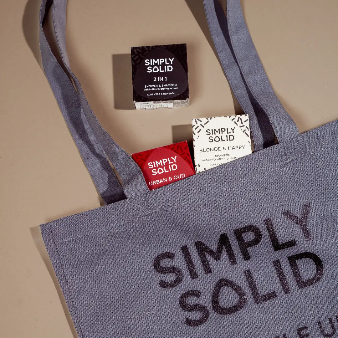 Eine Simply Solid Baumwoll-Tragetasche mit Aufdruck vor einem beigen Hintergrund.